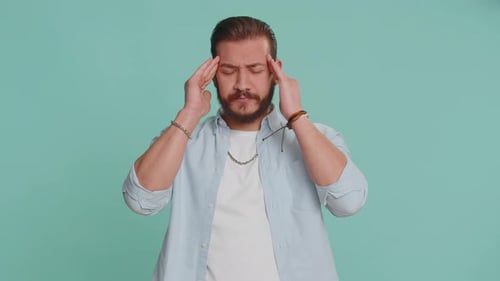Man Rubs Temples in Front of Blue Background