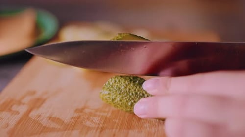 Close Up Hand Slicing Fresh Cucumber on Cutting Board