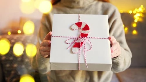 Woman Holds Christmas Gift with Festive Candy Cane