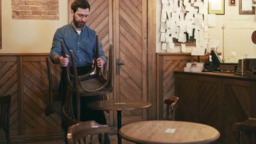 Restaurant Worker Lifting Chairs and Placed Them on Wooden Table at End of Day
