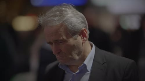 Man Ponders with Glasses at Corporate Event