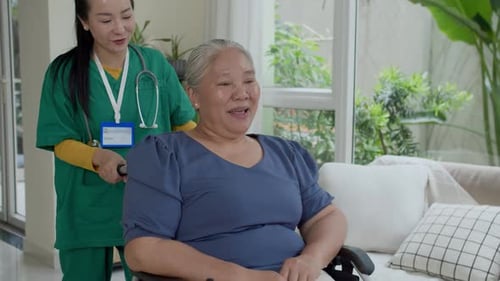 Nurse Pushing Senior Woman in Wheelchair at Home