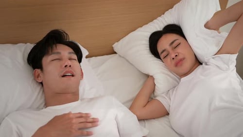 Couple dormant dans son lit avec un partenaire ronflant bruyamment