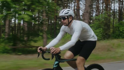 Sportler in Helm und Hemd fährt mit dem Fahrrad durch den Pinienwald