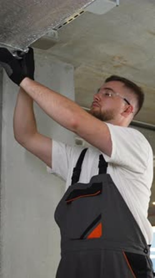 Man Installs Ceiling Fixture in Workplace with Screwdriver