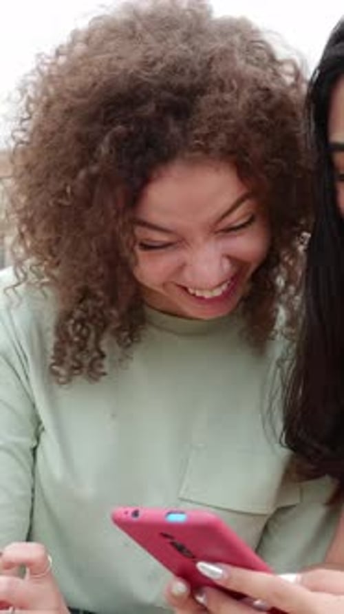 Two Women Friends Laughing at Mobile Phone