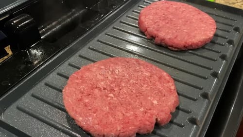 Hamburger raw beef patties cooking on grill at home, closeup