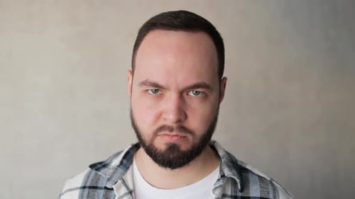 Bearded Man in Plaid Stares Seriously at Camera