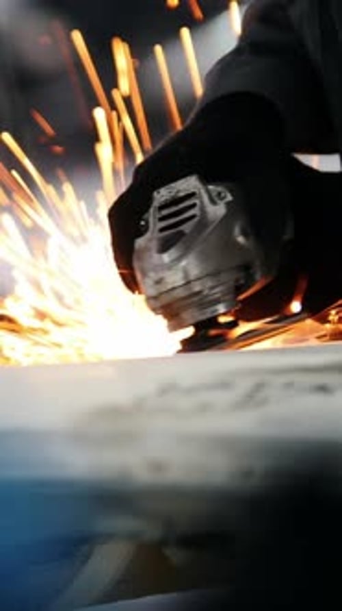 Car Service Worker Grinding Metal Construction with a Circular Saw