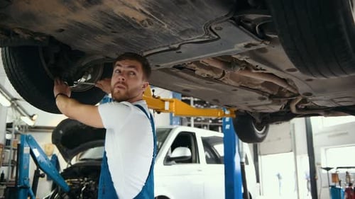 Mechanic Repairing Car Underneath in Auto Repair Shop