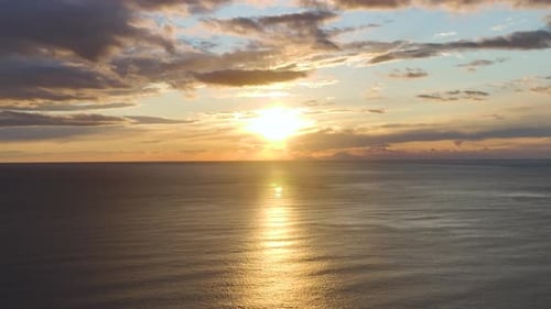 Vídeo aéreo del impresionante cielo nocturno lleno de cálidos colores del atardecer sobre un mar infinito