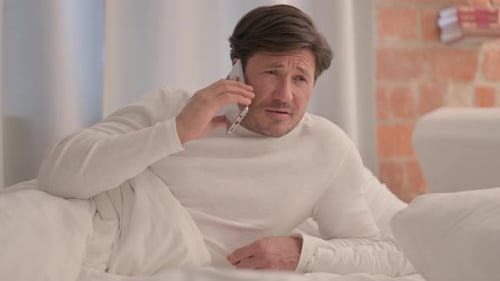 Homme adulte mûr parlant au téléphone au lit avant de s'endormir