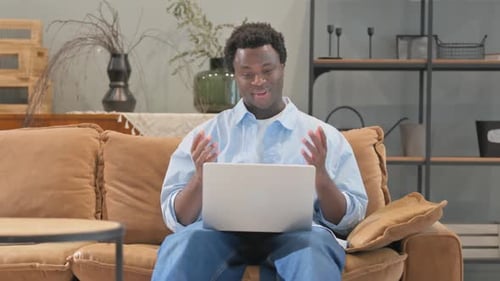 Young Adult Uses Laptop on Couch at Home
