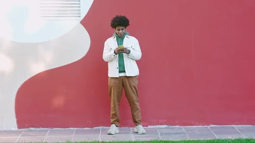 Smiling Young Man Using Phone Outside
