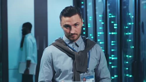 Ein konzentrierter Mann in einem Serverraum bedient ein Tablet, das Daten analysiert