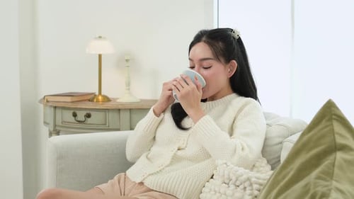 Woman Relaxing with a Mug on Sofa Indoors
