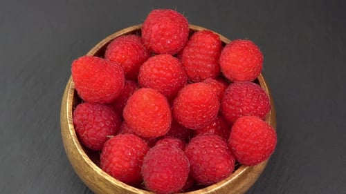 Ripe raspberries close up rotate in a wooden bowl. Juicy fresh raspberry berry is healthy