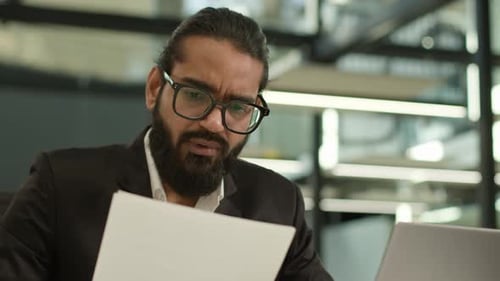 Adult Reviews Paperwork in Modern Office