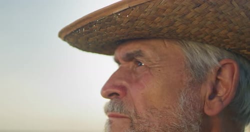 Portrait of Caucasian Senior Farmer Man in Hat and Looking at the Camera at the Field Farmland
