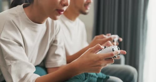 Couple Plays Video Games at Home on Couch