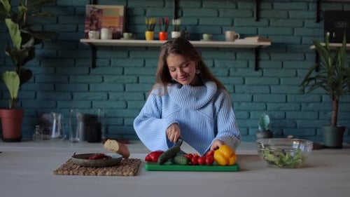Young Woman Cutting Vegetables for Salad in Kitchen