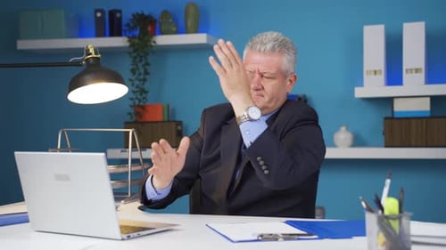 Stressed Man Types, Rubs Head at Office Desk