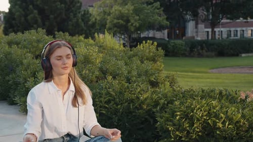 Young Woman Using Headphone for Listening Nice Music and Relaxing in City Park Girl Happiness Smile