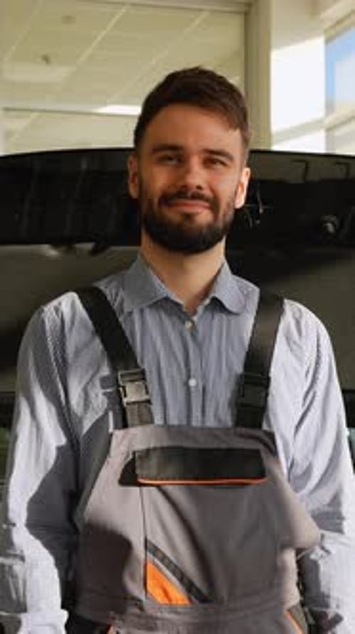 Mecânico de automóveis sorridente em frente ao capô aberto