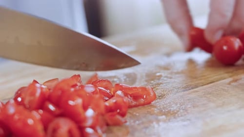Slicing Fresh Cherry Tomatoes on Wooden Board