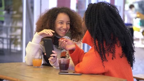 Girls Smiling and Looking at Phone Outside