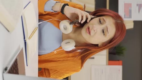 Woman Talking on Phone at Desk in Office