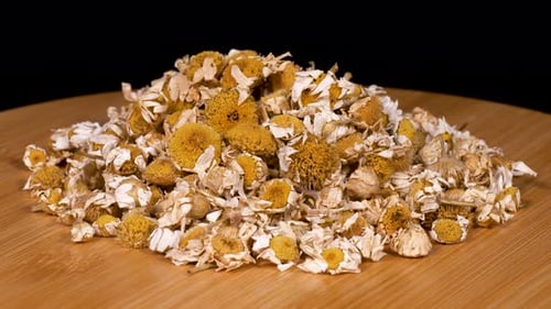 Pile of Dried Chamomile Flowers on Wood Surface