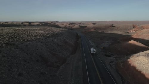 Traveling solo, a camper truck journeys across the road, traversing the barren expanses of Utah, USA