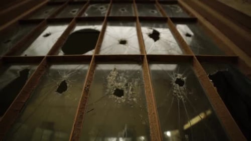 Slow dolly down of broken windows on the side of an abandoned mental insane asylum, dirty reflection