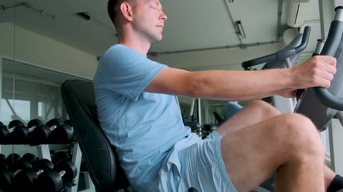 Man Working Out on Stationary Exercise Bike in Modern Gym Male Doing Cardio Training on Training