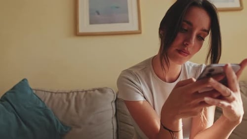 Young Woman Using Cell Phone on Couch Indoors