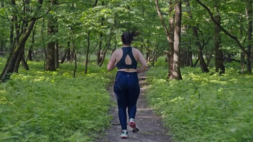 Caucasian Girl Jogging in the Forest in a Tracksuit