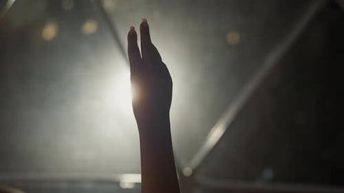 Hand Reaching Into Light in Darkness