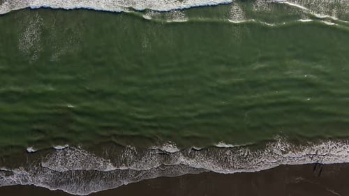 Scenic aerial bird's eye stationary shot of the Pacific Ocean with waves located in the Pacific Nort