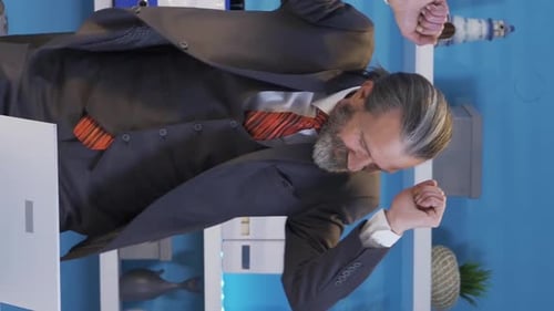 Vertical Video of Mature businessman working on laptop online in office, reading positive news.