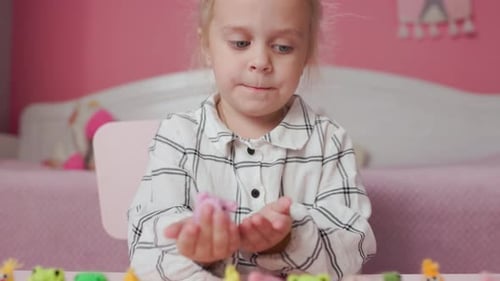 Mädchen spielt mit kleinen gestrickten Tierspielzeugen in einem Zimmer zu Hause