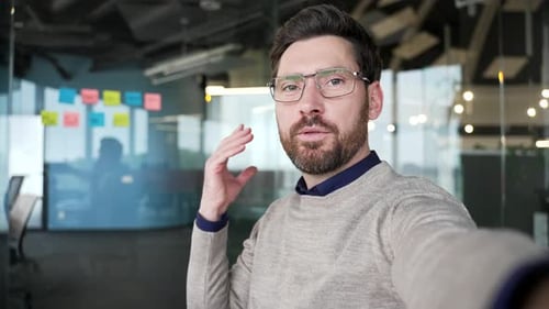 POV confident businessman talking on video call using smartphone in modern office. Handsome mature