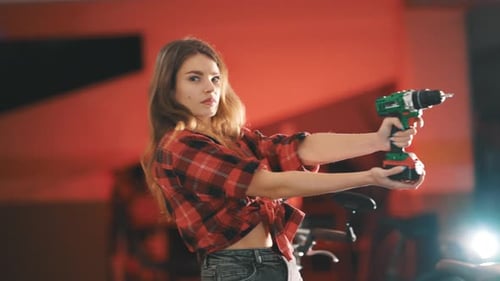 Confident Young Woman Holding Cordless Drill in Garage
