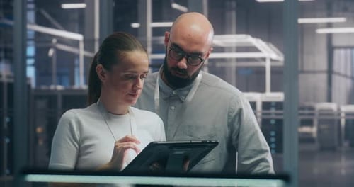 Männliches und weibliches IT-Ingenieurteam arbeiten zusammen und diskutieren Daten, die auf einem digitalen Tablet angezeigt werden