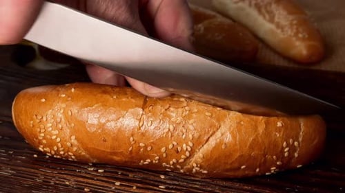 Hands Slice Sesame Seed Bun With Knife