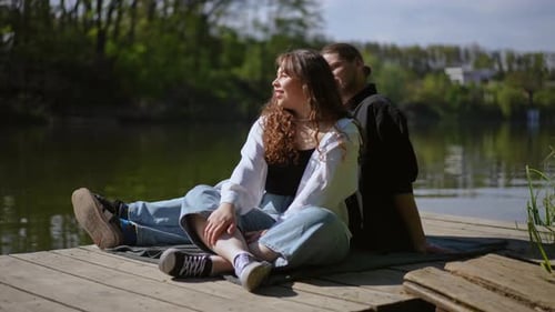 Relaxing Couple Sitting on a Pier by a Lake