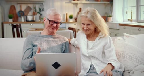 Senior Couple Video Chatting on Laptop at Home
