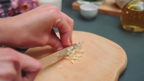 Close Up Hand Chopping Garlic on Board