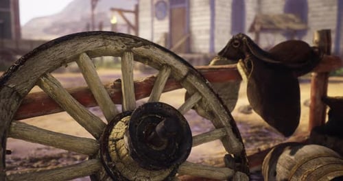Rustic Wagon Wheel and Saddle in a Historical Village Setting During Daylight