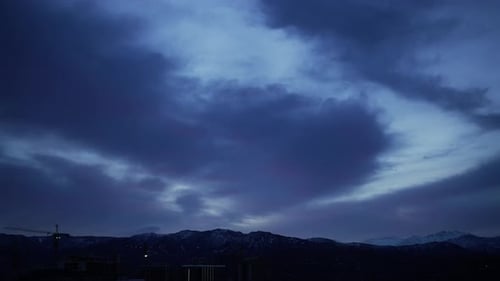 Dramatisch Morgenhimmel über der Berglandschaft mit Silhouetten von Gebäuden im Zeitraffer